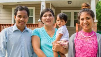 A family stands in front of their home.