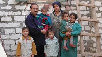 Photo: a family with 5 children, a new wall of their future house in the background