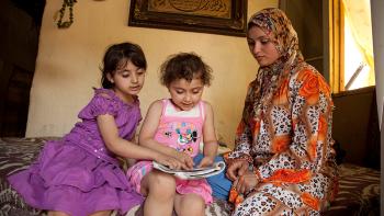 Inside a flat in Lebanon - two girls and their mother reading a book together 