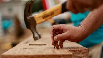 Volunteer hammers a nail into wood.