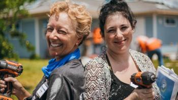 Jessica holds a drill outside a Habitat home.