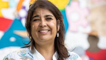 Woman smiling in front of colorful mural.