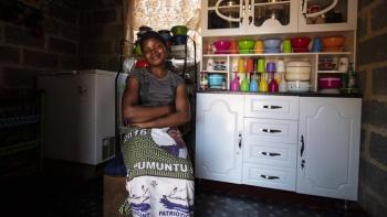 Habitat homeowner Lucy smiling in a chair inside her home.