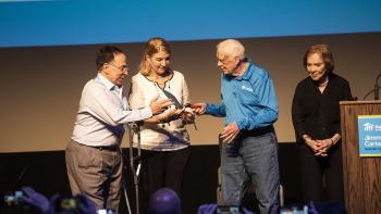 Former President Jimmy Carter passes a ceremonial trowel to Cesarina Fabián.