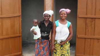 Photo: Two women and a child in front of a newly constructed latrine