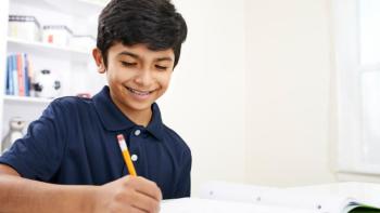 A boy smiles as he does his homework.