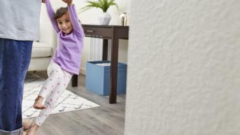 Little girl dances on father’s feet in the living room.  