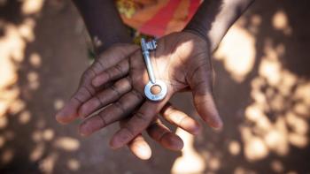 A young girl, who lives in a Habitat for Humanity Zambia home with her mother and her cousin, holds the key to her front door.