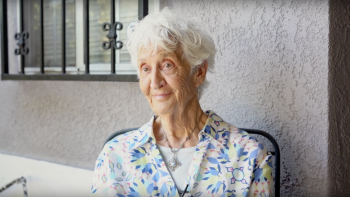 Older adult Rachel sits outside her home.