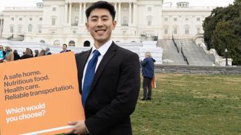 Man holding sign in Washington, D.C. that says "A safe home. Nutritious food. Health care. Reliable transportation. Which would you choose?"