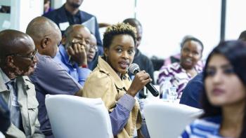 Woman speaking into a microphone in a crowd at ShelterTech Kenya event.