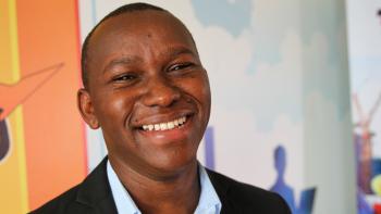 Man smiling in front of colorful background at ShelterTech Kenya event.