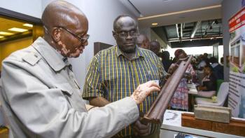 Man examining building material prototype at ShelterTech event.