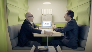 Two participants sit at a booth together and talk.