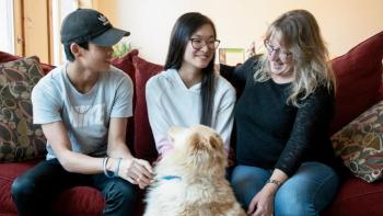 Candance and her two kids sit on their couch with their Golden Retriever dog on their floor.