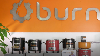 A sign reads "burn" and several prototypes sit below it on a table.