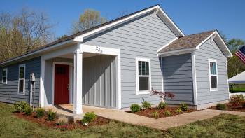 New Habitat house with blue siding and a red door.