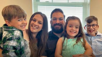 Family of five smiling inside their home.