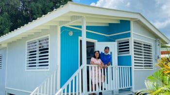 A homeowner stands with his mother on the porch of their blue and white house.