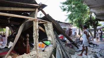 Photo taken by Nadia Todres of Hatian woman standing in front of the rubble of a collapsed home.