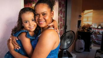 Woman holding her young daughter in their home.