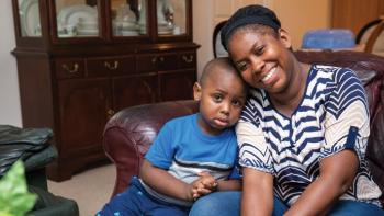 Mother and young son sitting together on their couch.