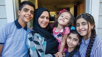 Woman in headscarf with her four children in front of their home.