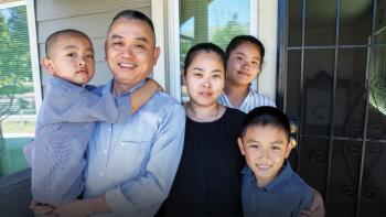 Family of five posing together on their front porch.