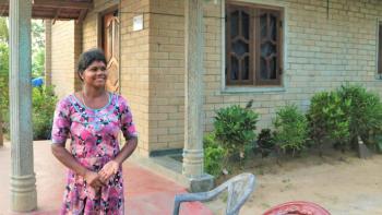 Thushanthini in a floral dress outside her home.