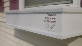 Window flower box with "Continue to thrive in your beautiful home!" written on it with Drew and Jonathan Scott's signatures