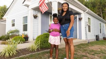 Smiling mother and daughter outside home