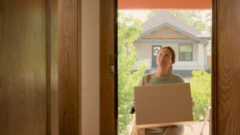 A woman stands in the doorway of her home, her safe place.
