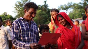 A smiling family looks at a land tenure document.