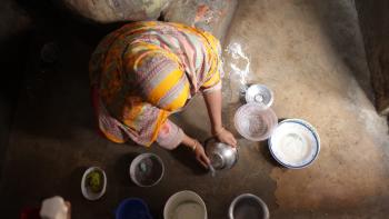 Overhead shot of woman washing cooking dishes on the floor of her home.
