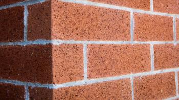 Closeup on the corner of a precisely laid red brick wall.