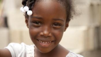 young girl with beads in hair smiling at camera