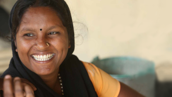 Nepalese woman in black hijab and warm yellow shirt smiling