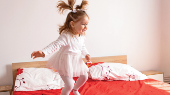 Little girl with pigtails jumping on bed
