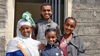 Family of four standing in front of home