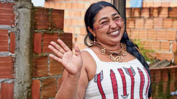 Smiling woman waving and wearing traditional clothing