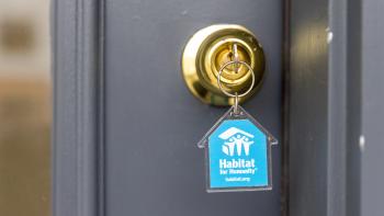 Photo of key in lock with blue, house-shaped Habitat keychain
