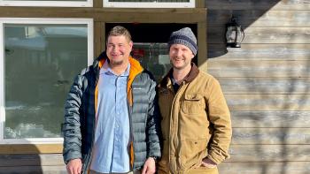 Two men stand in front of a house