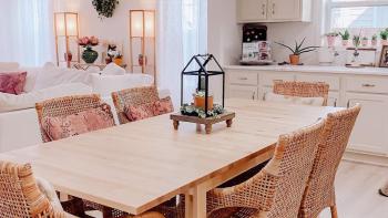 A brightly lit room with a light wood table as the focal point.