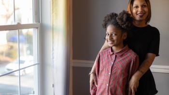 Photo of smiling woman and child in front of sunny window