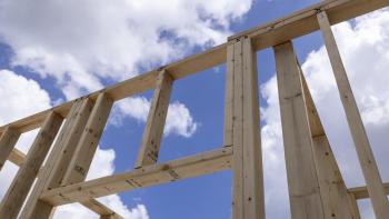 Wood framing of house from low angle with blue sky and clouds in background