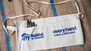 Habitat for Humanity tan workers apron with blue logo. Nails in the left pocket on top of butcher paper and painters tape. 