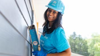 A woman on a ladder wearing a blue heardhat.