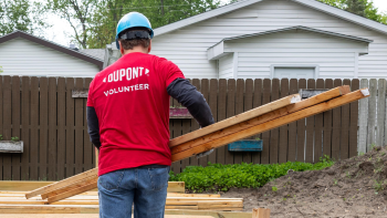 A DuPont volunteer carries materials at a Habitat jobsite.