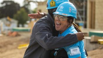 man and woman volunteer hugging at build site