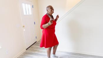 Mujer vestida de rojo celebrando en la entrada de su nuevo hogar.